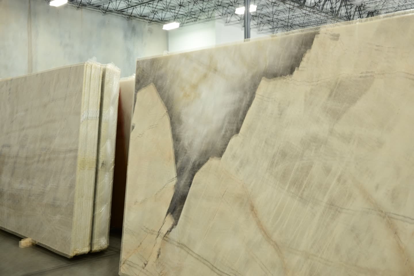 A large pale slab with a dark sweeping plume of veining, standing beside further stacked slabs.