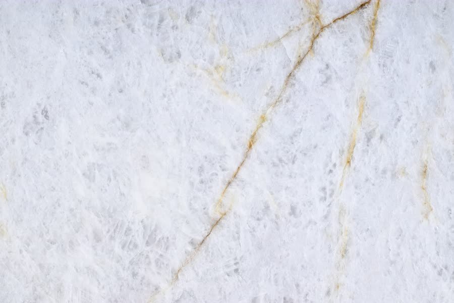 Close-up of a Crystallo Traslux slab: white crystalline stone crossed by branching amber and gold veins.