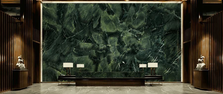 Rendered interior visualisation of a symmetrical lobby with a full-height dark green veined stone feature wall behind a long low desk, flanked by fluted panelling, backlit ceiling trim and two lit table lamps.