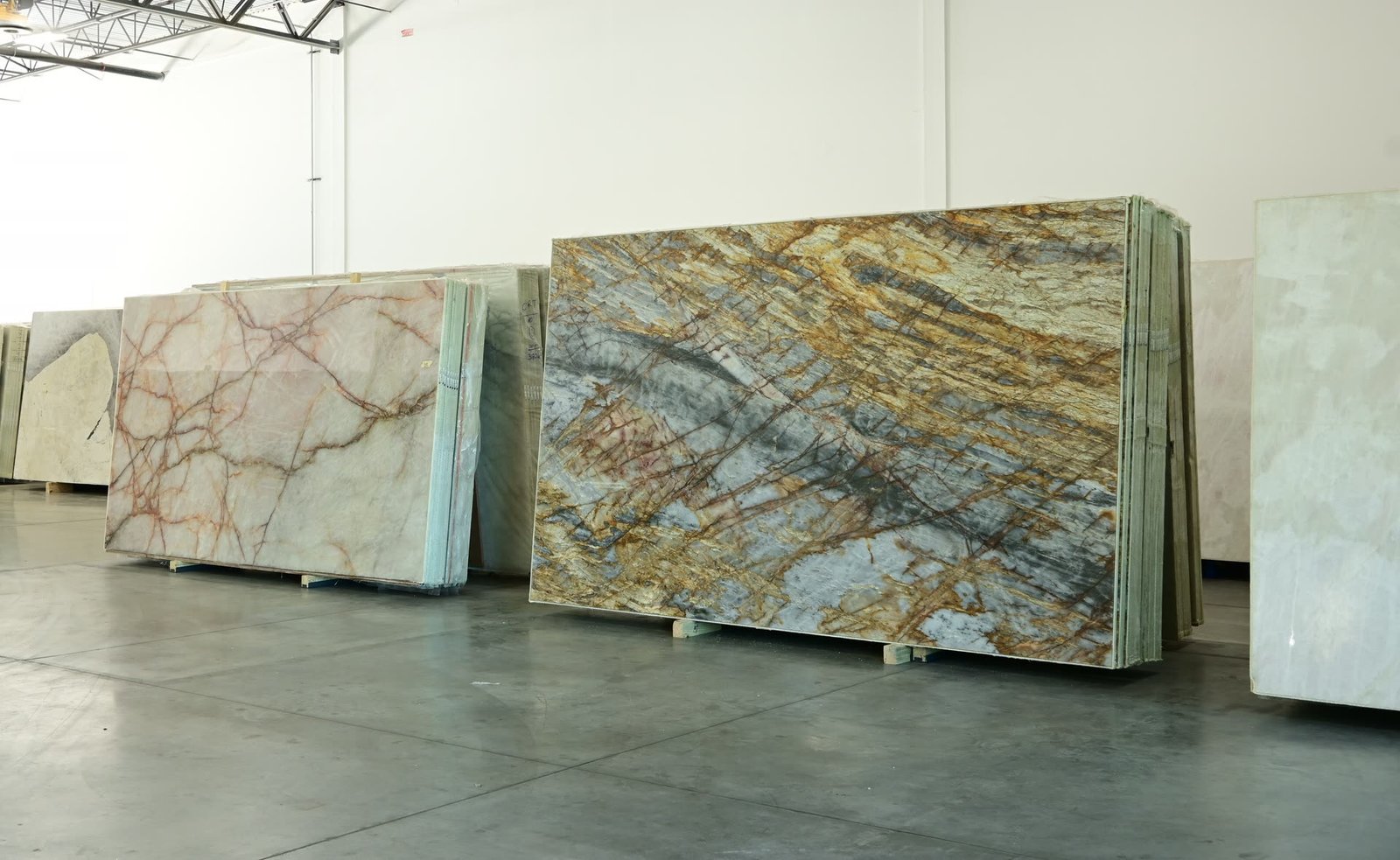 A row of stone slabs on the showroom floor, with a gold and blue-grey veined slab standing at the centre.
