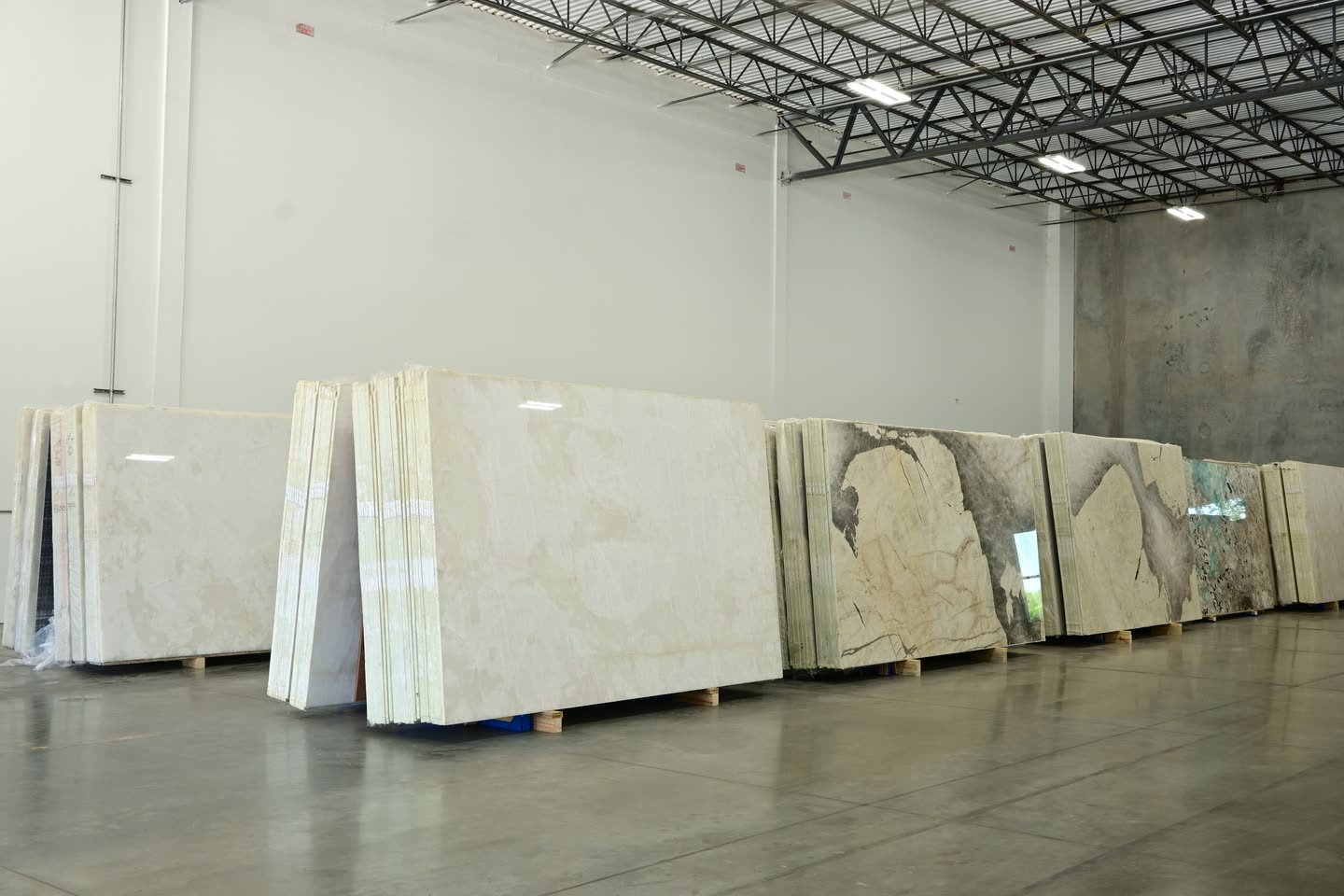 A wide view of the showroom floor with slab bundles stacked in rows along both walls.