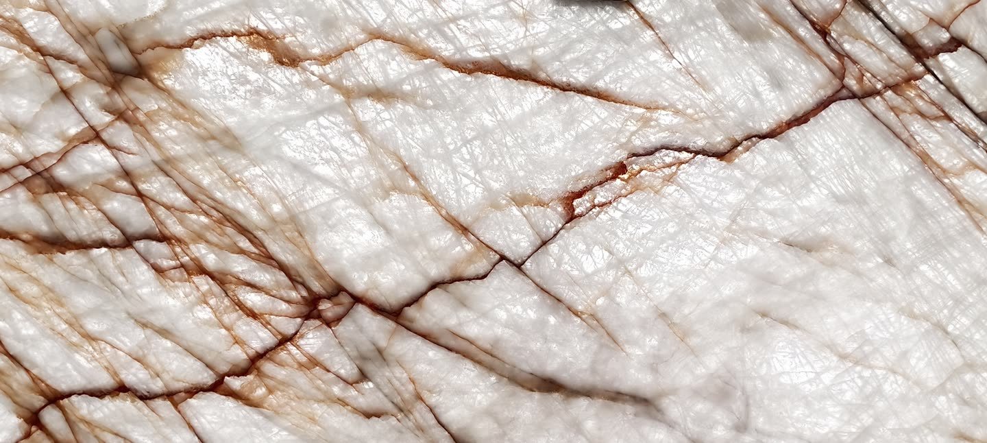 Rosso Crystallo — the slab lit from behind so the translucency and vein structure read through the stone.