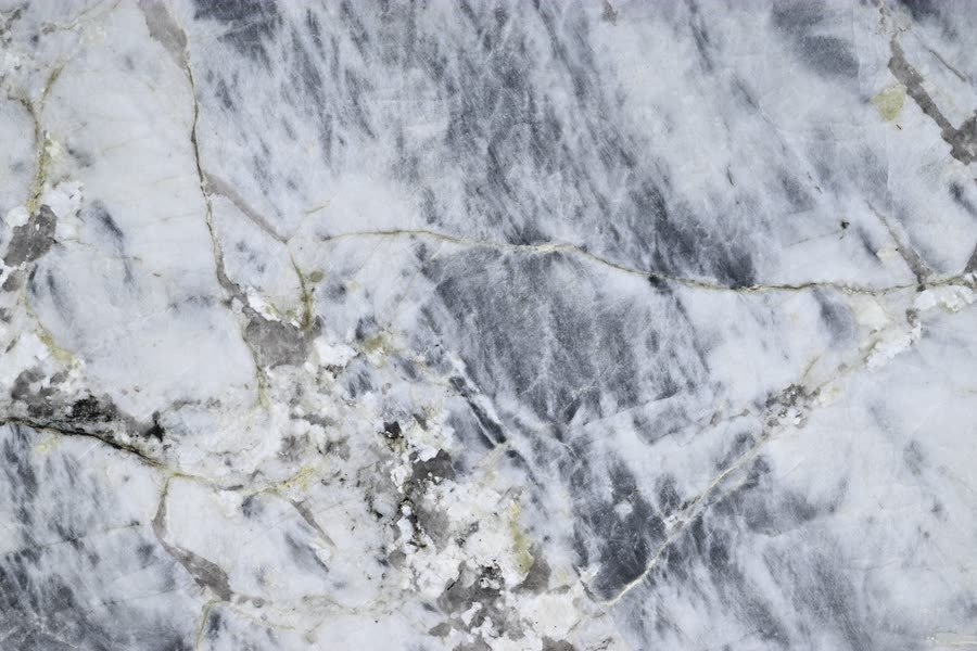 Blue Alpine — close view of the stone surface. Cool grey and white crossed by soft blue-grey drift.