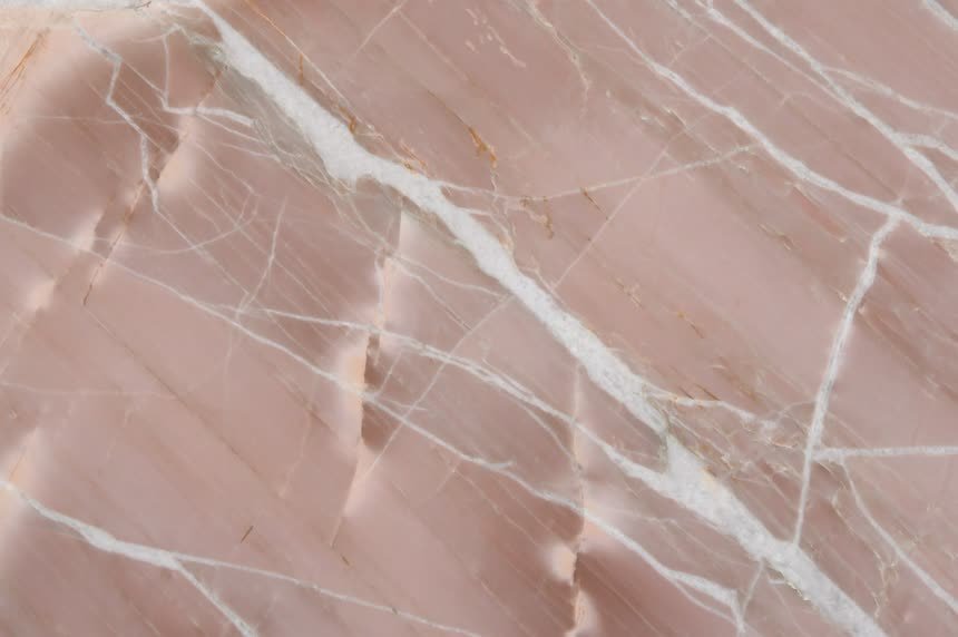 Splendido Brown — close view of the stone surface. Rose-pink ground with pale veining.
