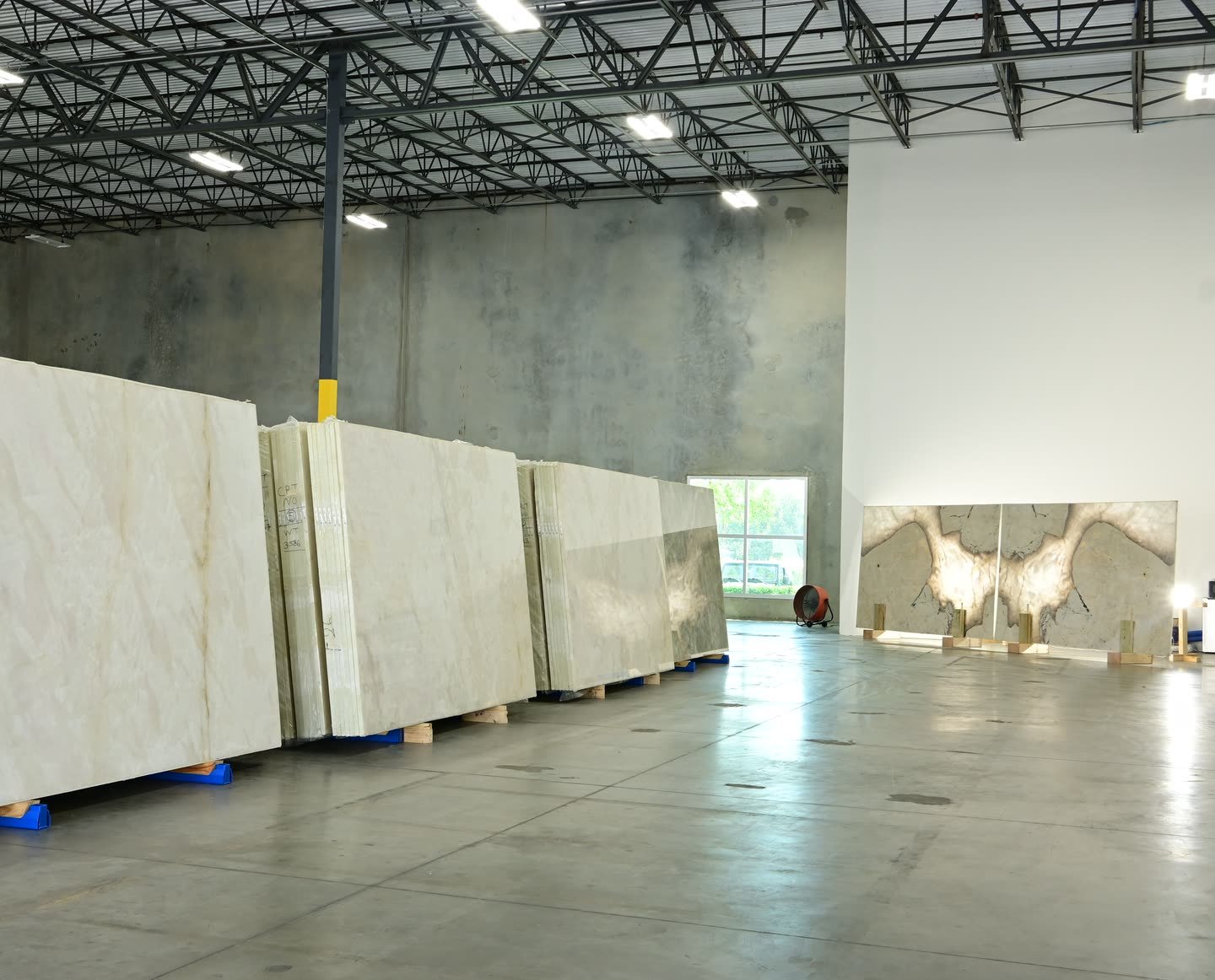 A row of cream slabs on the showroom floor with a mirrored dark-veined pair standing against the far wall.